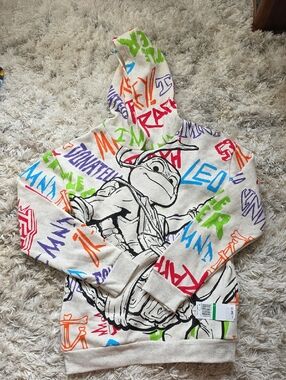 Nickelodeon Cream Hoodie with Black Turtle Graphic and Multicolor Graffiti